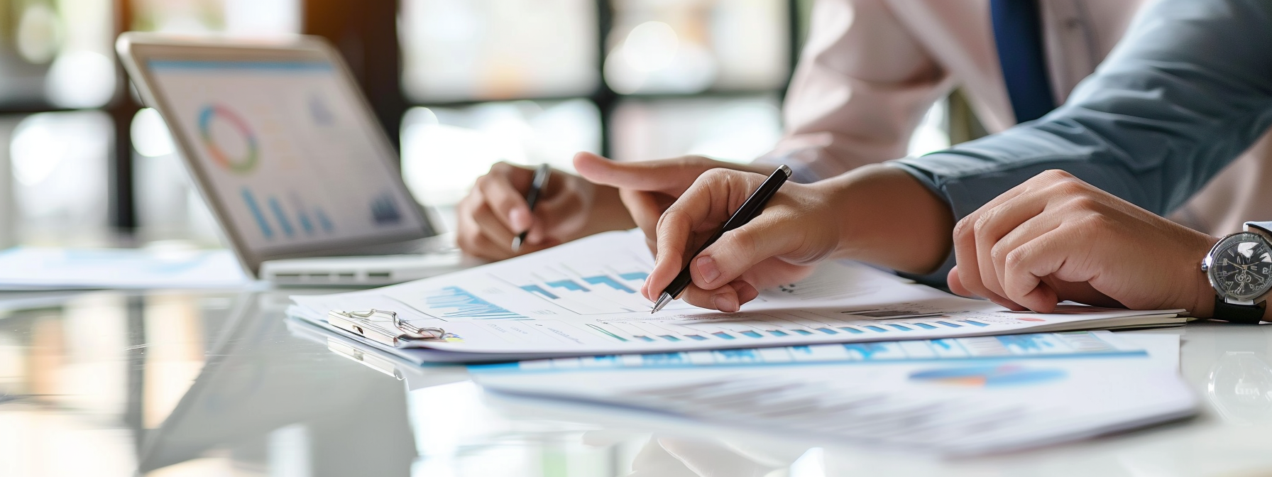 Two professionals reviewing printed financial statements together at a desk, one taking notes
